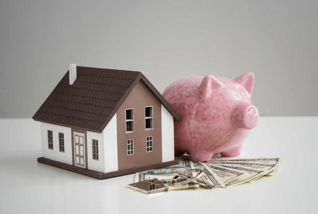 Model house beside a piggy bank with cash and keys, illustrating Illinois condominium developer reserve funding obligations.