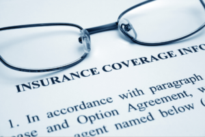 Reading glasses resting on a printed insurance coverage policy — Illinois D&O insurance and condo board duty to defend.